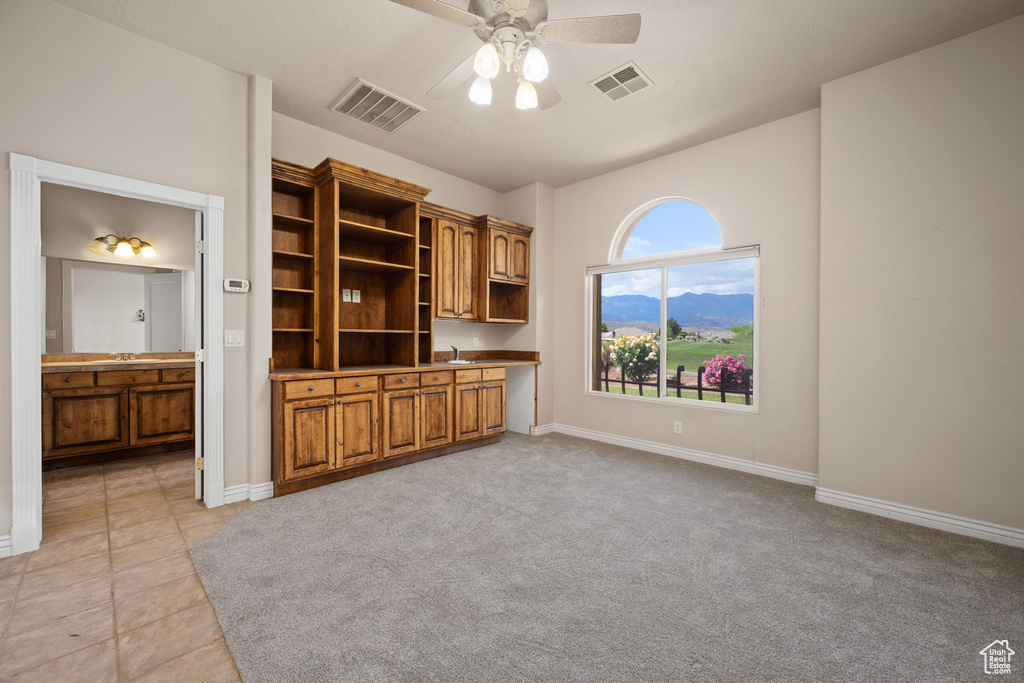 Unfurnished living room with a ceiling fan, baseboards, and a sink