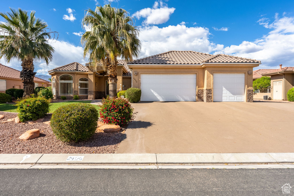 Mediterranean / spanish-style house with concrete driveway, an attached garage, stone siding, stucco siding, and a tile roof
