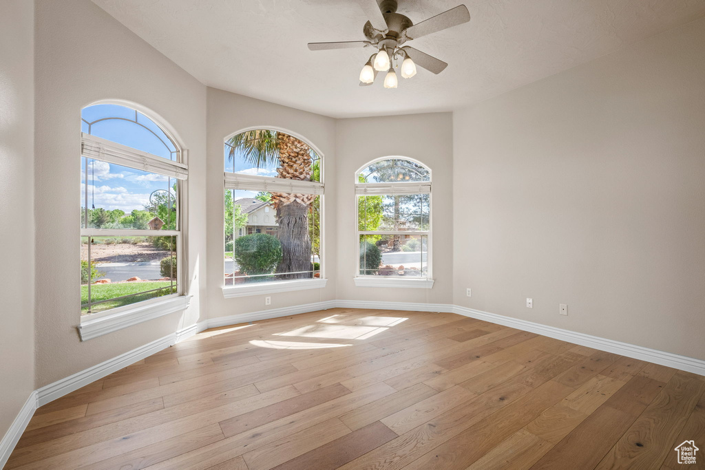 Spare room featuring baseboards, light wood-type flooring, and a ceiling fan