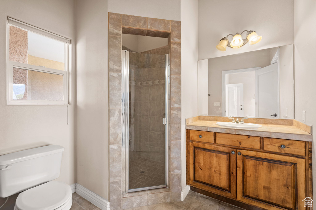 Full bath featuring a stall shower, baseboards, toilet, vanity, and tile patterned flooring