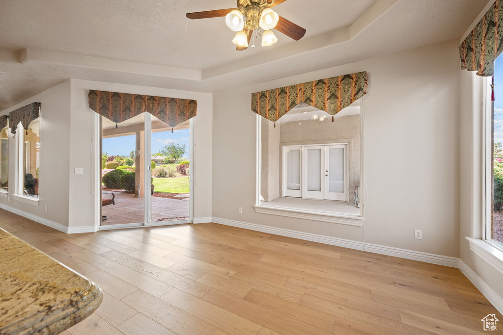 Unfurnished room featuring light wood-type flooring, ceiling fan, healthy amount of natural light, and baseboards