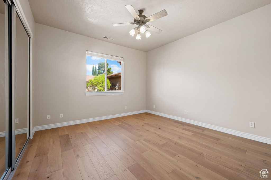 Unfurnished bedroom with baseboards, light wood-type flooring, a closet, and a ceiling fan