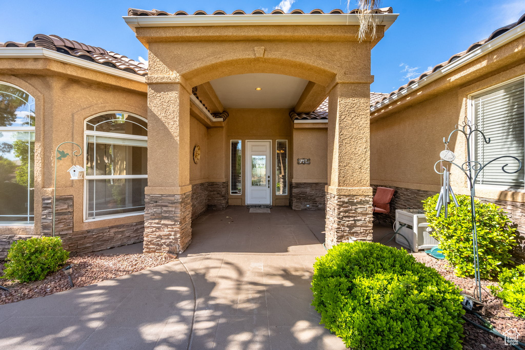 Property entrance featuring stone siding, stucco siding, and a tiled roof