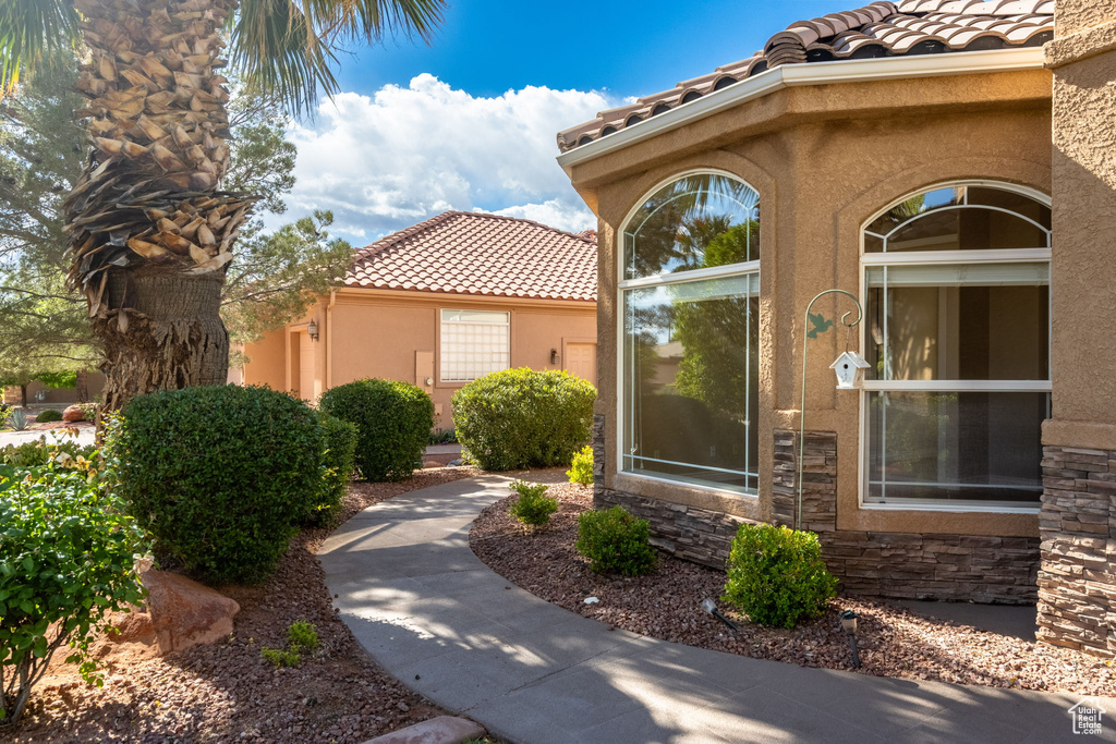 Property entrance featuring a tiled roof, stucco siding, and stone siding