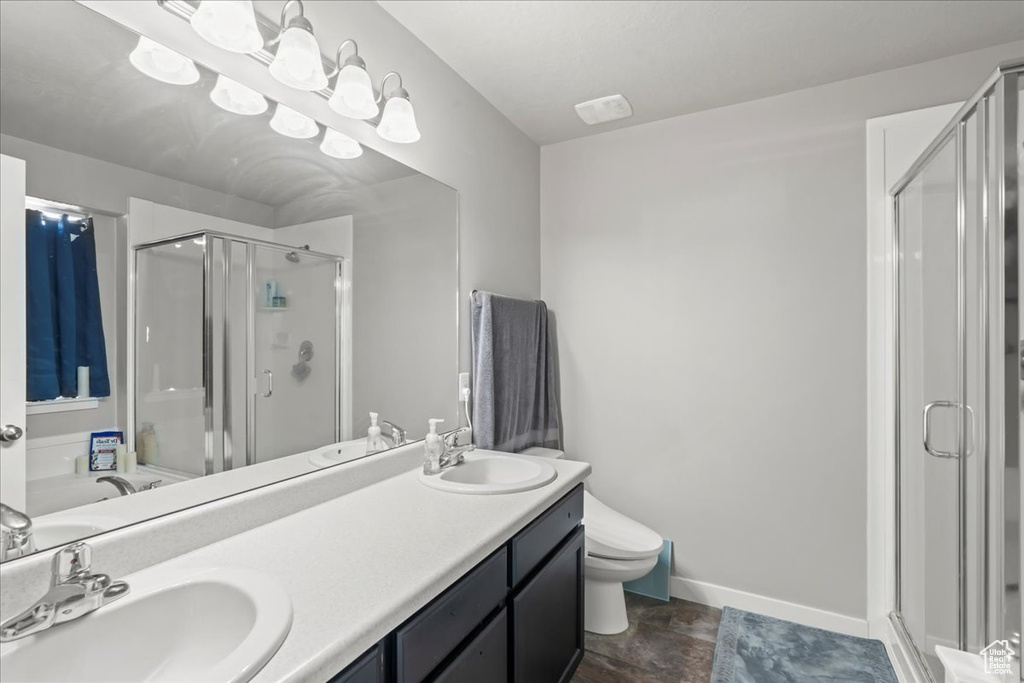 Bathroom with a sink, baseboards, a shower stall, and double vanity