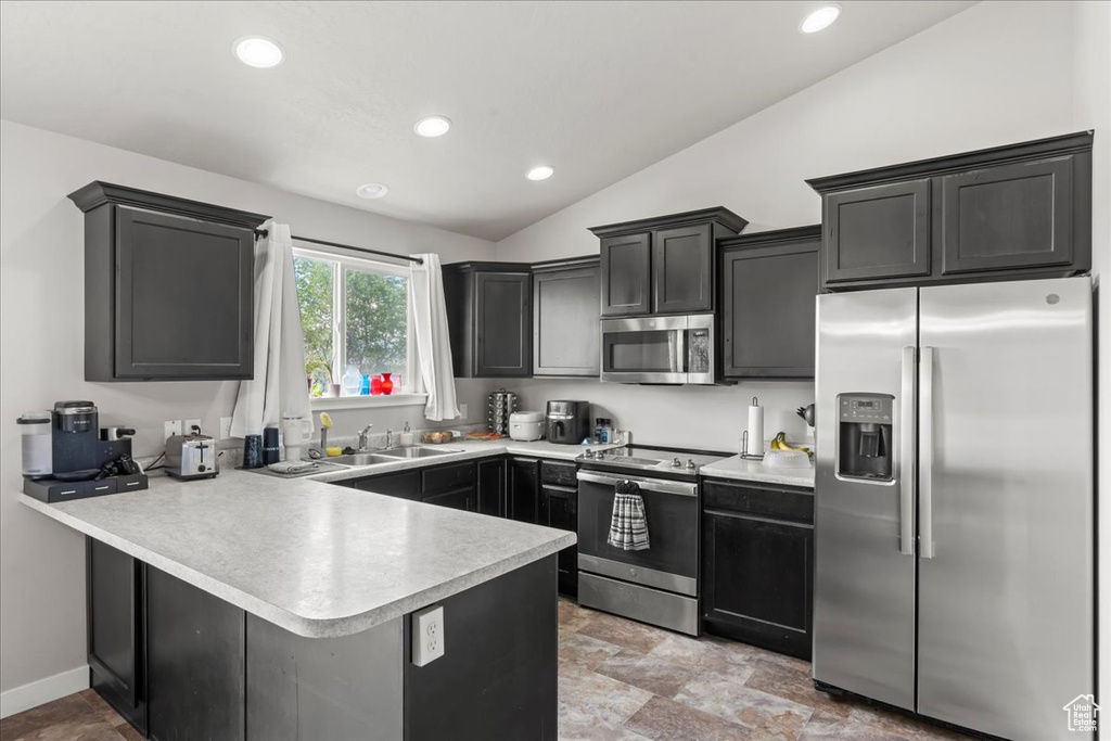 Kitchen with a peninsula, recessed lighting, light countertops, a sink, and stainless steel appliances