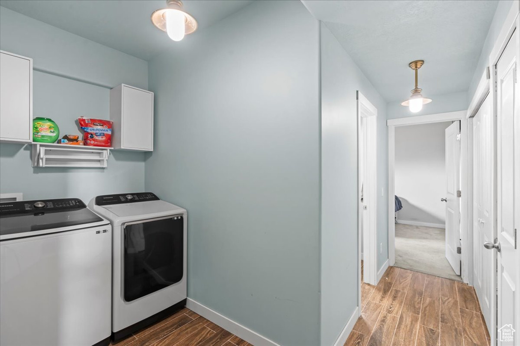 Clothes washing area with cabinet space, separate washer and dryer, baseboards, and wood finished floors