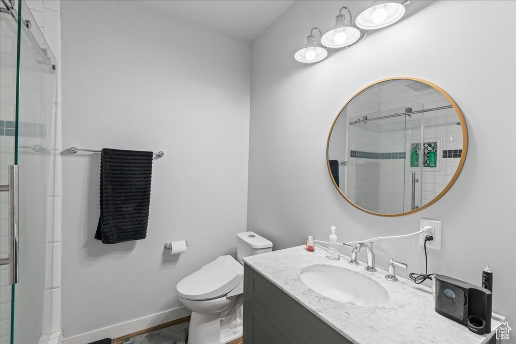 Bathroom featuring vanity, baseboards, a stall shower, and toilet