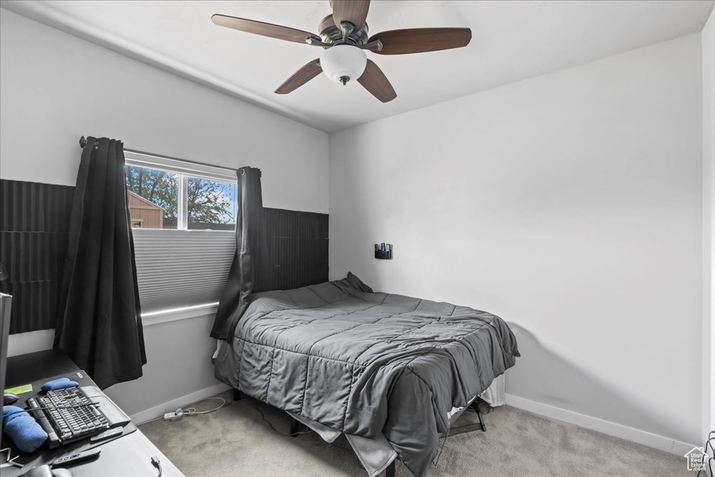 Bedroom featuring baseboards, a ceiling fan, and light colored carpet