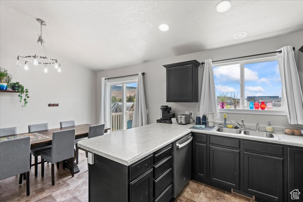 Kitchen with dishwasher, a sink, light countertops, a peninsula, and dark cabinetry