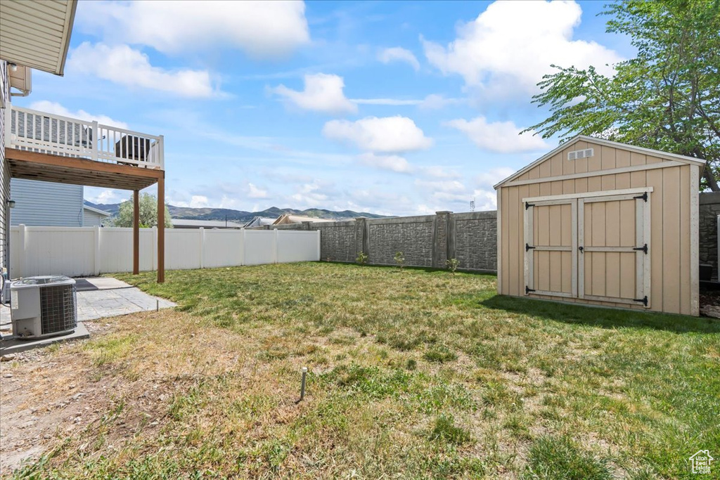 View of yard featuring a fenced backyard, a storage unit, an outdoor structure, and central AC
