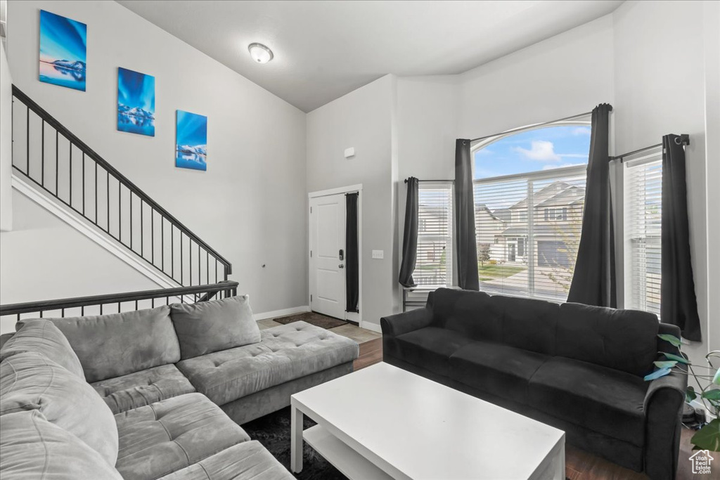 Living room featuring baseboards, a towering ceiling, wood finished floors, and stairway