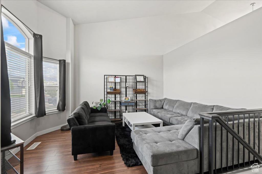 Living area with baseboards, dark wood finished floors, a wealth of natural light, and vaulted ceiling