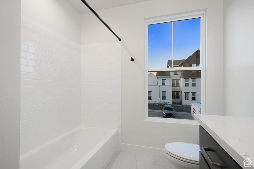 Bathroom with marble finish floors, toilet, baseboards, shower / tub combination, and vanity