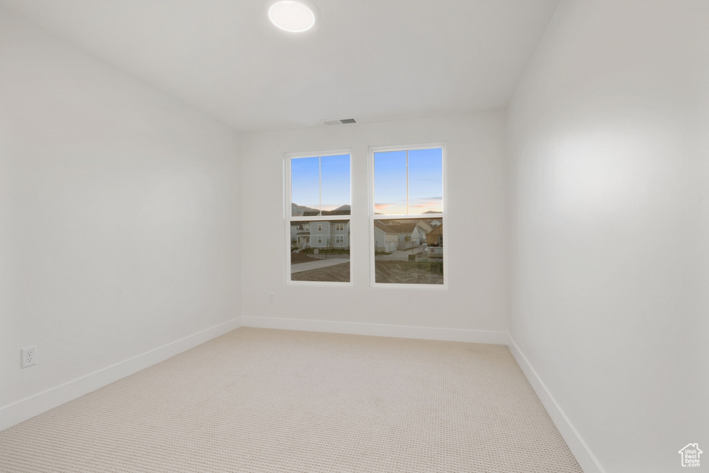 Spare room with baseboards and light carpet