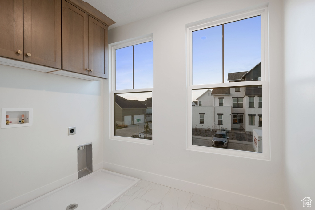 Laundry area with electric dryer hookup, cabinet space, hookup for a washing machine, marble finish floors, and baseboards