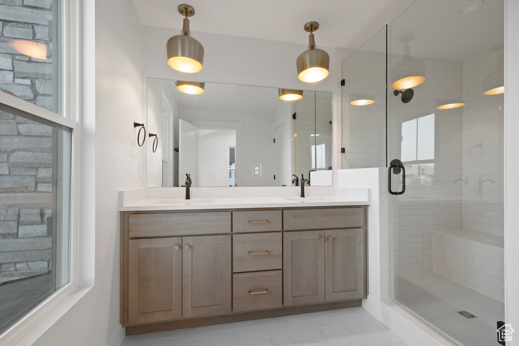 Bathroom with a shower stall, double vanity, and marble finish flooring