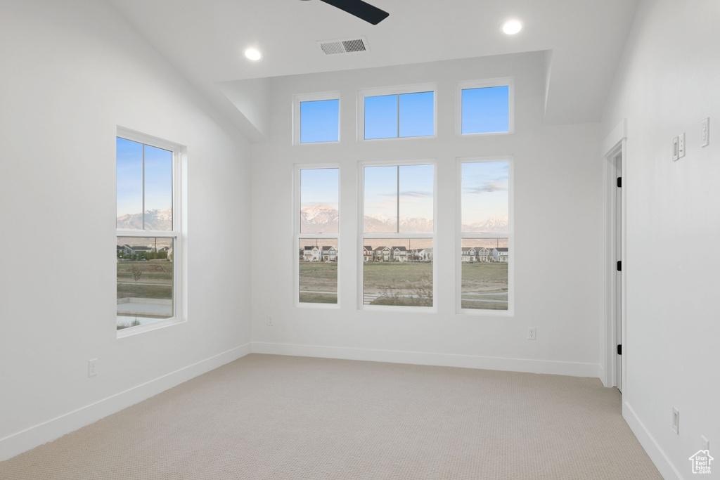 Unfurnished room featuring healthy amount of natural light, light colored carpet, baseboards, recessed lighting, and a ceiling fan