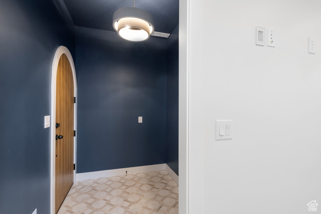 Foyer entrance with arched walkways, light floors, and baseboards