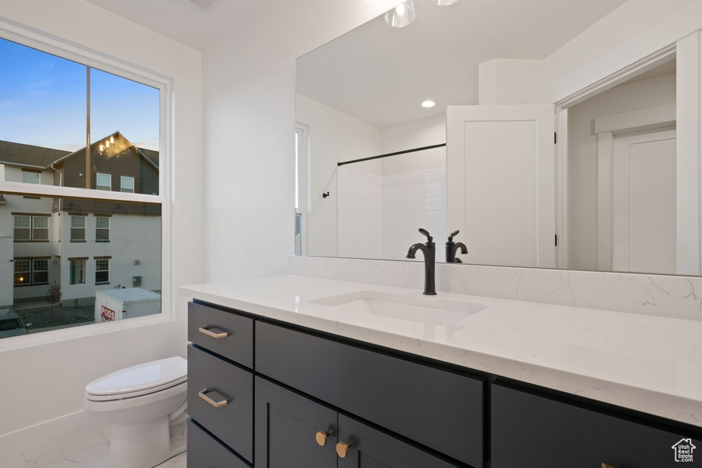 Full bathroom with marble finish flooring, toilet, vanity, and a shower