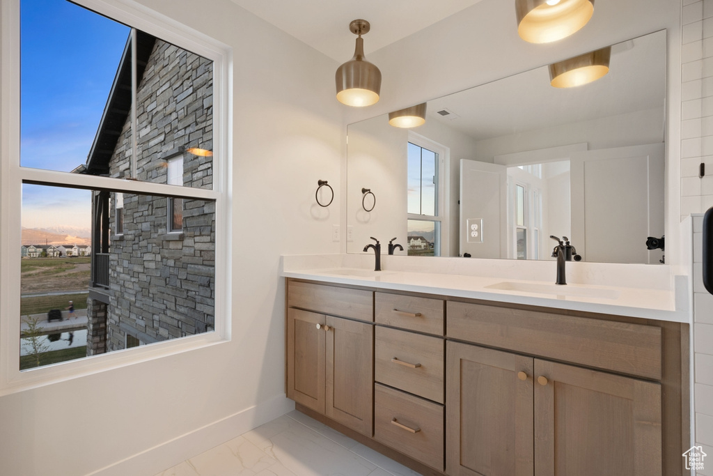 Full bath featuring baseboards, marble look tiles, and double vanity