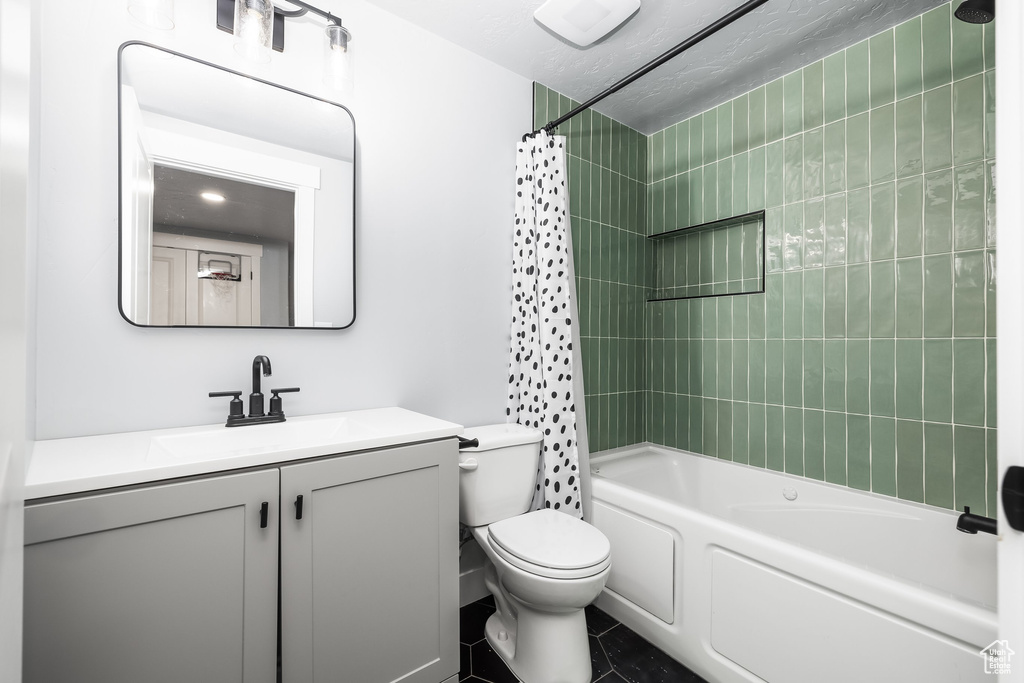 Full bathroom featuring shower / tub combo with curtain, toilet, vanity, and tile patterned floors