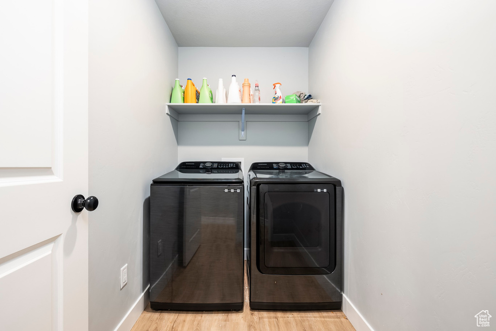 Laundry room featuring washer and clothes dryer, light wood finished floors, and baseboards