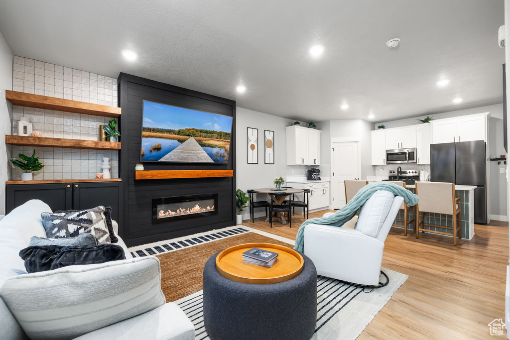 Living room featuring a large fireplace, light wood-type flooring, and recessed lighting
