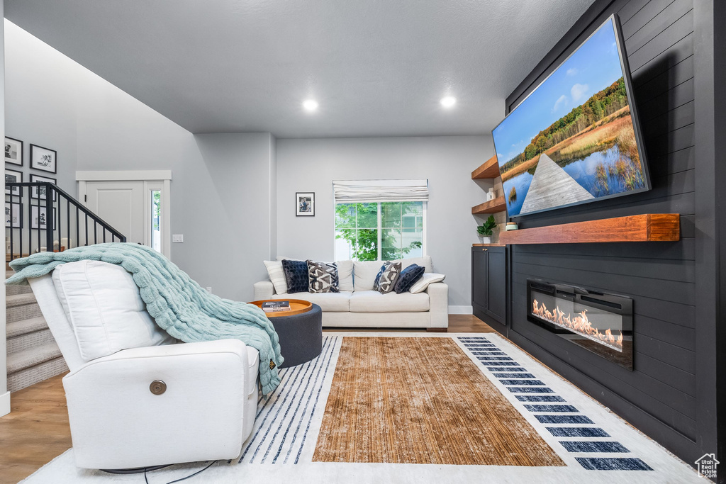 Living area with a fireplace, wood finished floors, stairway, and recessed lighting