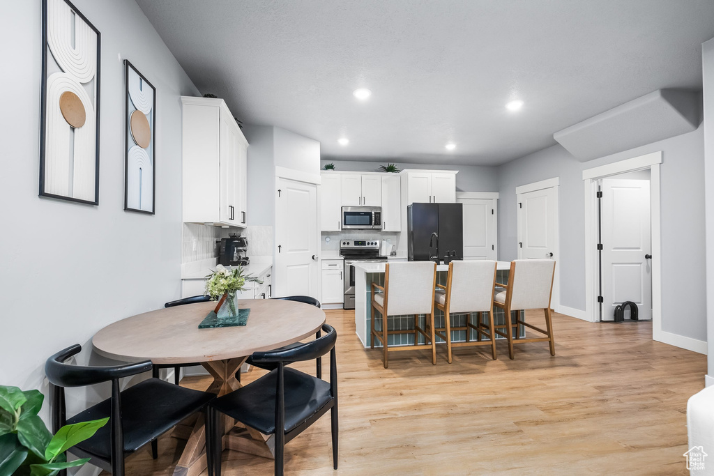 Dining room with recessed lighting, light wood finished floors, and baseboards