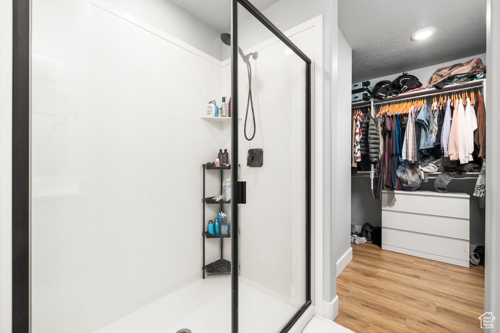 Bathroom featuring a stall shower, a walk in closet, wood finished floors, and recessed lighting