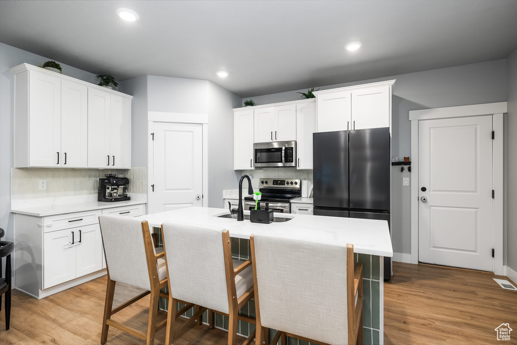 Kitchen with stainless steel appliances, a sink, decorative backsplash, light countertops, and recessed lighting