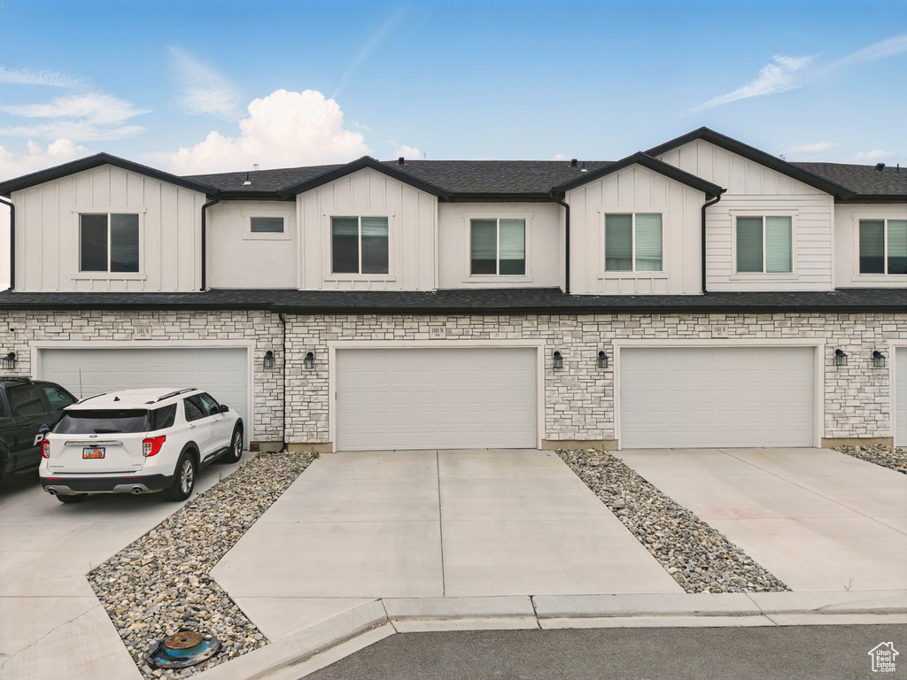 Townhome / multi-family property featuring a garage, board and batten siding, and driveway