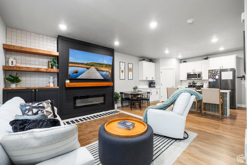 Living room featuring light wood-style floors, recessed lighting, and a fireplace