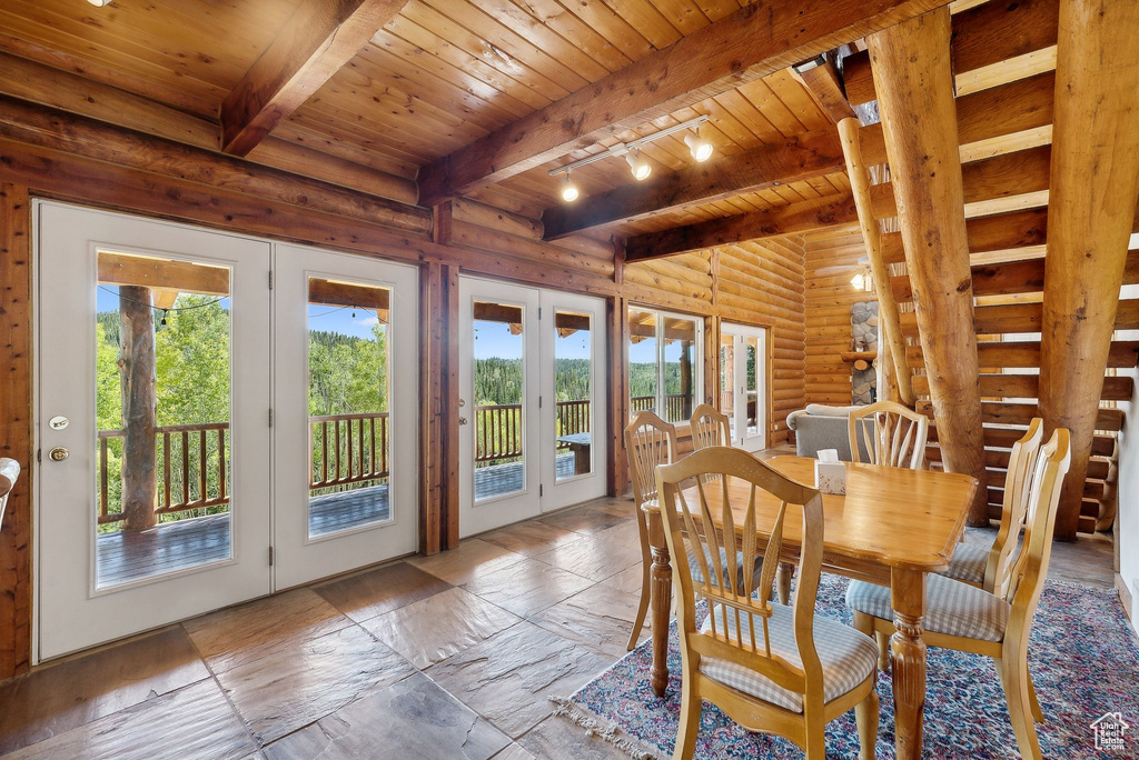 Dining space with french doors, wooden ceiling, rustic walls, beamed ceiling, and healthy amount of natural light
