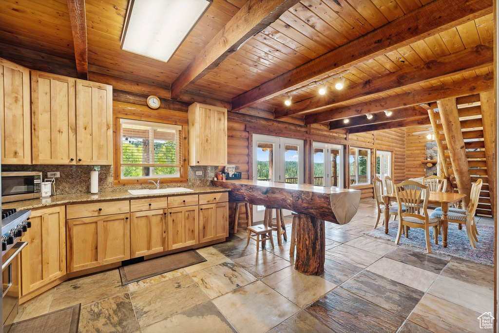 Kitchen with light brown cabinets, rustic walls, stainless steel appliances, wooden ceiling, and french doors