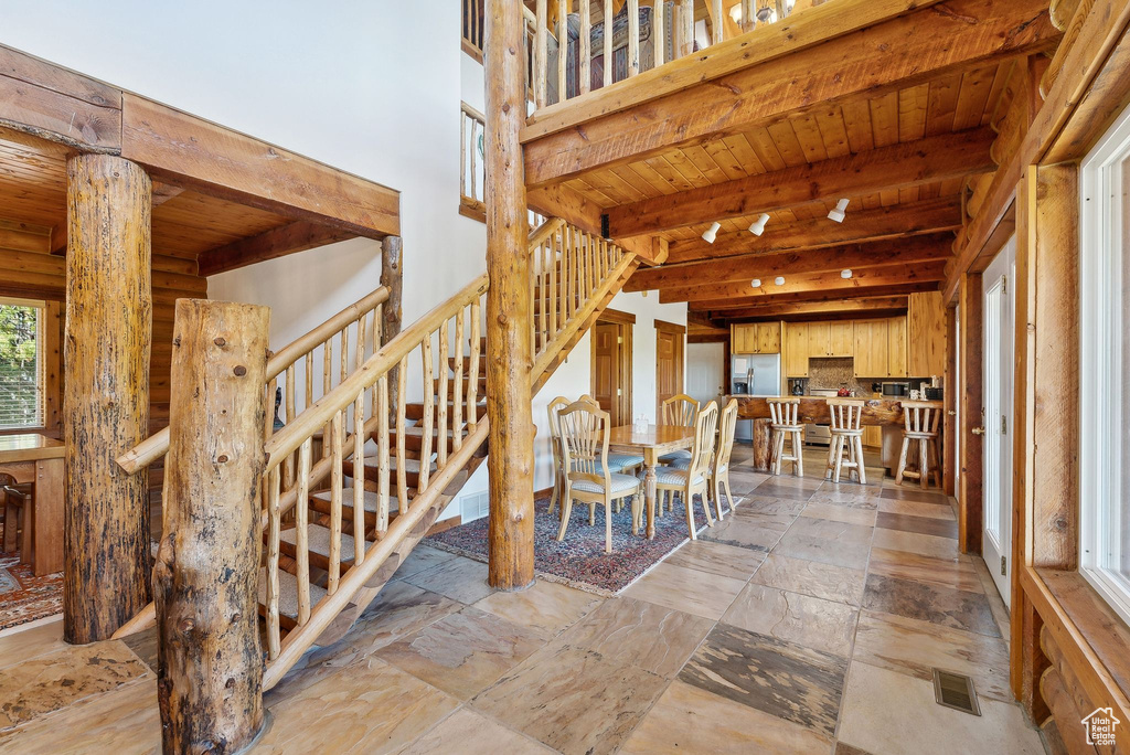Staircase featuring wood ceiling, beam ceiling, and stone tile floors