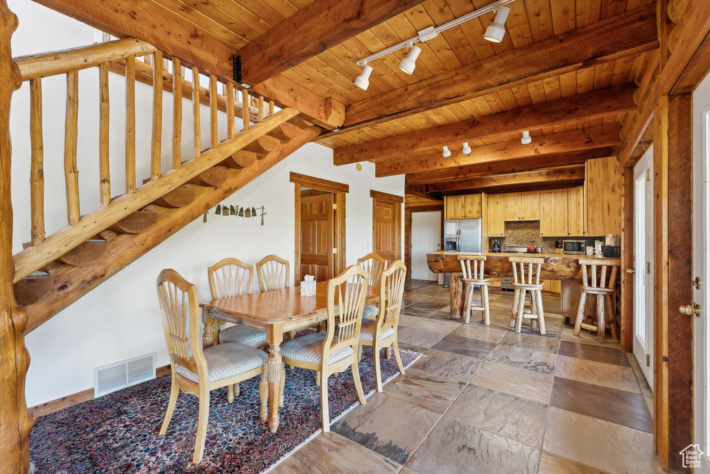 Dining area featuring rail lighting, wood ceiling, beam ceiling, and stairs