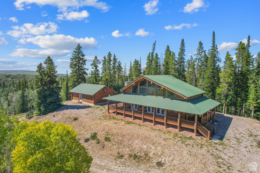 Back of property featuring a porch, a wooded view, and metal roof