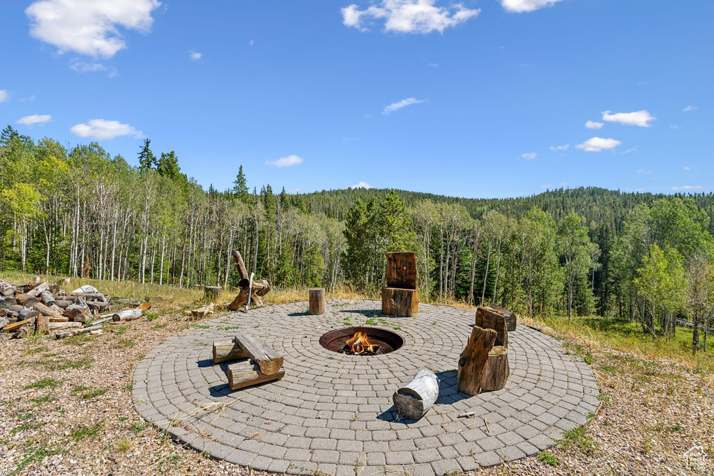View of patio with a wooded view and an outdoor fire pit
