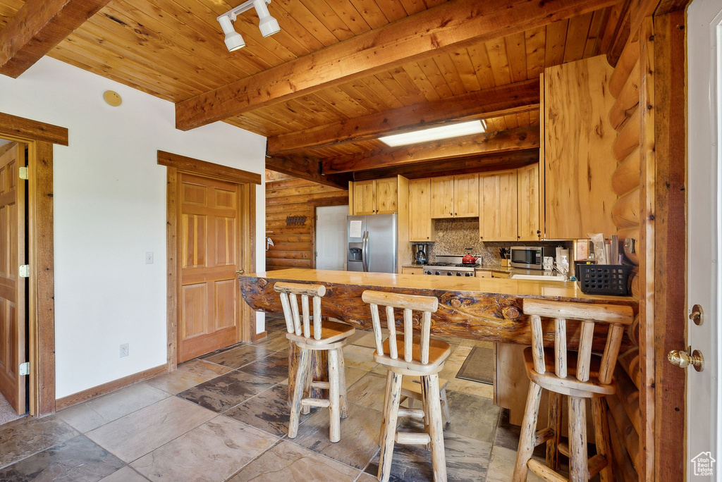 Kitchen featuring stainless steel appliances, beamed ceiling, wooden ceiling, a peninsula, and baseboards