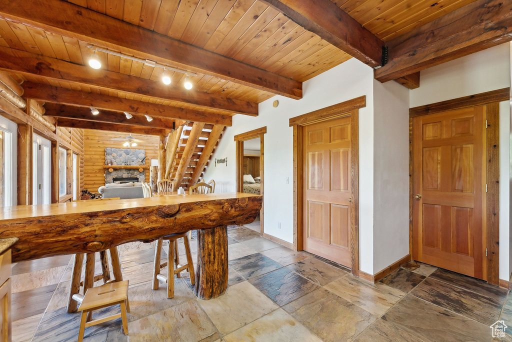 Recreation room with baseboards, beamed ceiling, wood ceiling, stone finish floors, and a fireplace