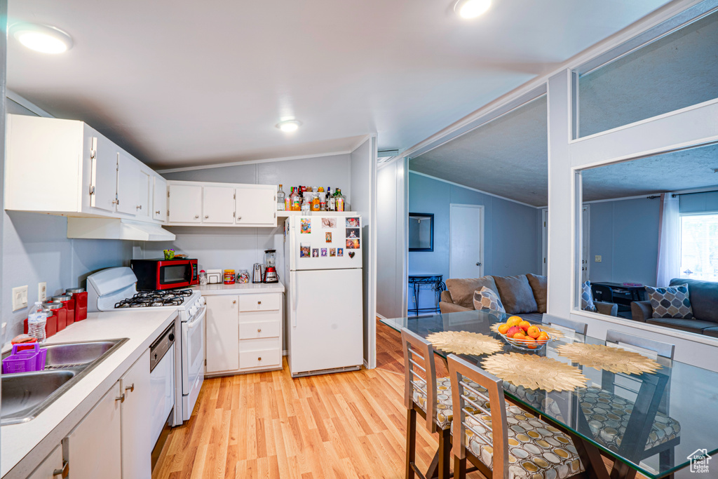 Kitchen featuring white appliances, vaulted ceiling, light wood finished floors, white cabinetry, and light countertops