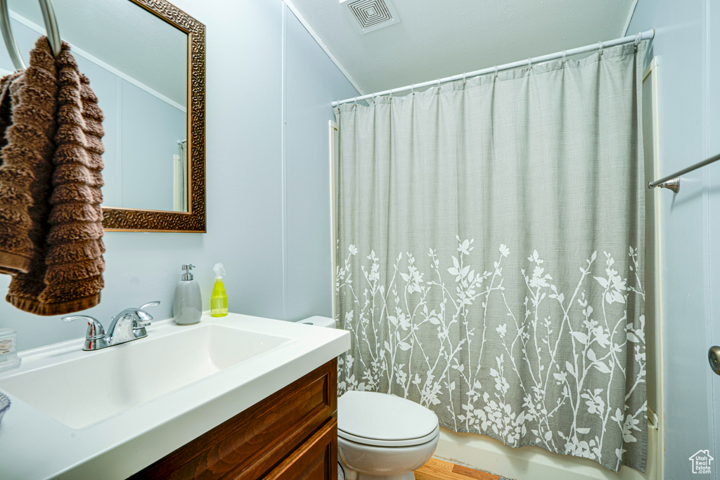 Bathroom featuring toilet, vanity, and shower / bath combo with shower curtain