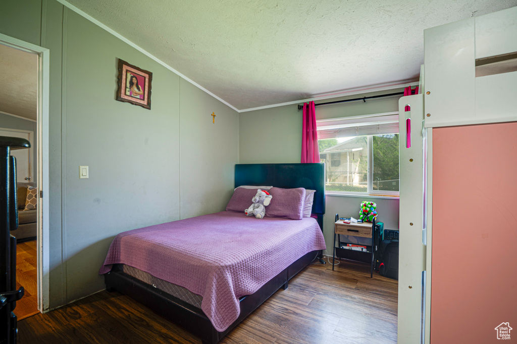 Bedroom with wood finished floors and crown molding