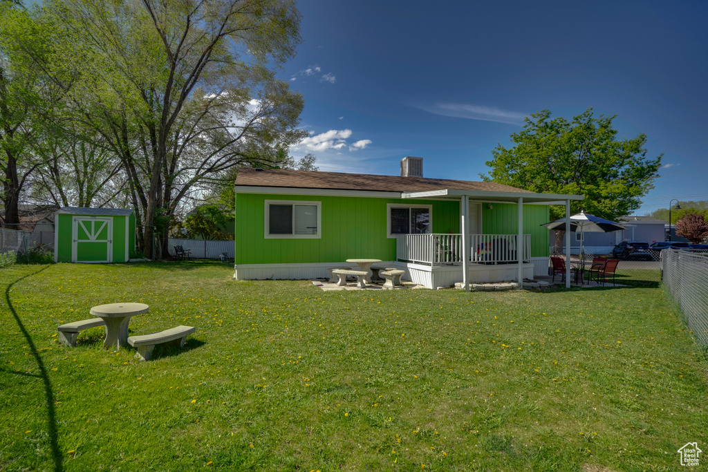 Rear view of house featuring a storage unit, an outdoor structure, a chimney, and a porch