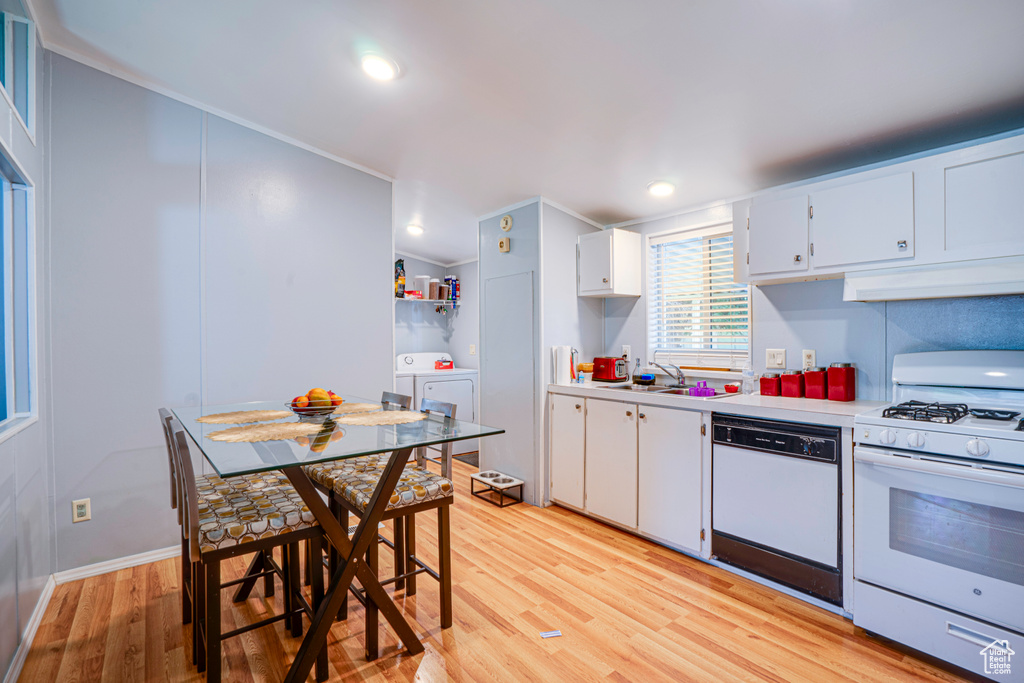 Kitchen featuring white appliances, under cabinet range hood, light countertops, light wood-style flooring, and a sink