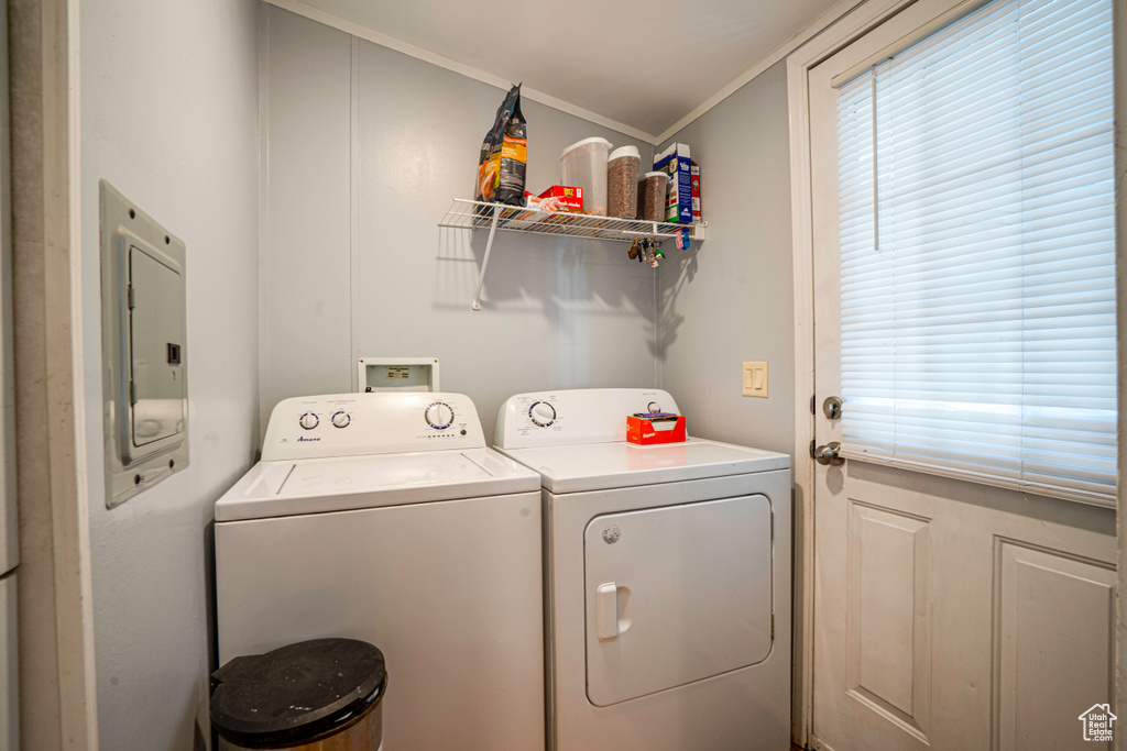 Clothes washing area featuring washing machine and clothes dryer, electric panel, and ornamental molding