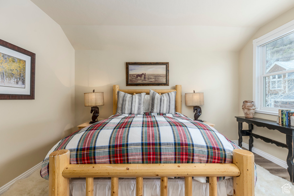 Bedroom featuring lofted ceiling and baseboards