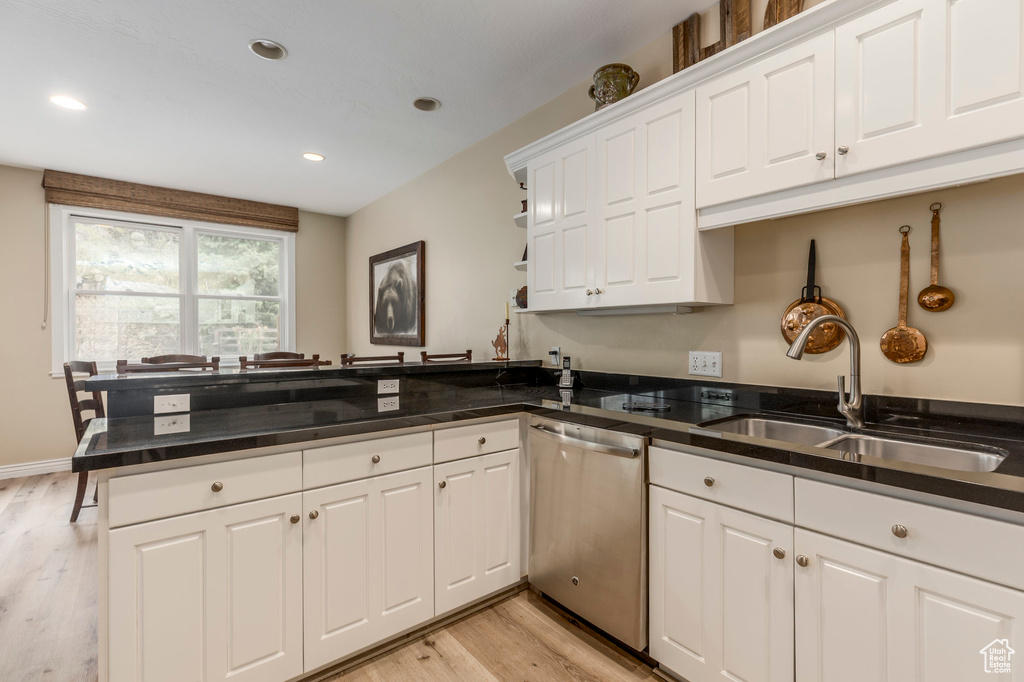 Kitchen with dishwasher, a sink, a peninsula, dark countertops, and recessed lighting